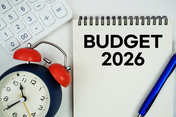 Budget 2026 text written on notepad with alarm clock and calculator on white background