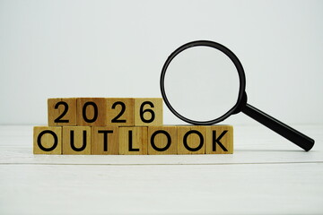 2026 Outlook alphabet letters with magnifying glass on wooden background
