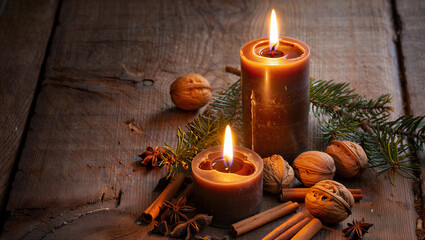 Warm glowing candles and festive natural decorations including pine cones and cinnamon sticks on rustic wooden background Second Day of Advent
