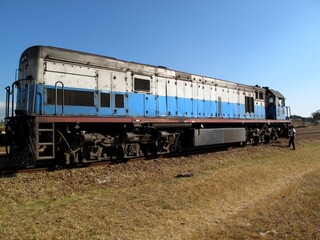 Obraz premium TAZARA diesel locomotive on rural railway tracks with a worker standing beside it in East Africa, Tansania.