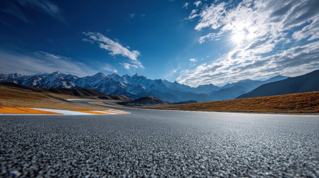 Asphalt road leading towards majestic snowcapped mountain range under sun - Powered by Adobe