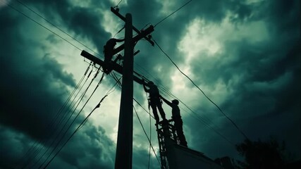 silhouette of lineworkers repairing power lines on utility pole against dark stormy sky. dangerous electrical maintenance work. emergency service, industrial background.