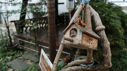 A quaint wooden birdhouse hanging from a tree branch, with intricate details, blending into a serene outdoor setting.