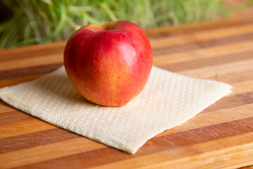Fresh Red Apple on Cloth Napkin on Wooden Table in Natural Light Kitchen Setting Close-Up