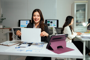 Asian businesswoman smiling and holding blank sign in office