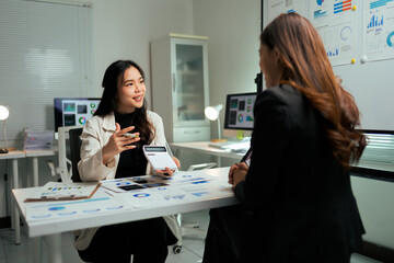 Businesswomen discussing finance, analyzing data in modern office