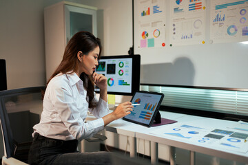 Woman analyzing business data using tablet in office