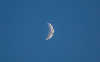 New moon in a blue sky. Crescent moon. Close-up of the moon in the evening or night sky.