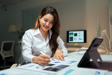 Asian businesswoman analyzing data and charts working late