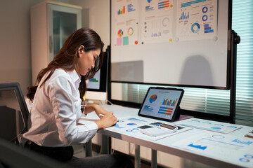 Businesswoman analyzing data graphs and business reports late
