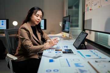 Businesswoman analyzing corporate data graphs using tablet at night