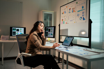 Businesswoman talking on phone and analyzing data late at office