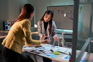 Businesswomen analyzing data together during late night meeting