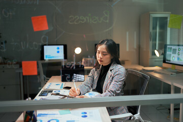Businesswoman working late analyzing data in office