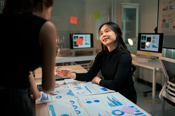 Businesswomen analyzing data discussing project strategy in office meeting
