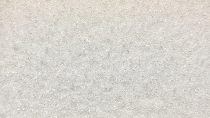 close-up abstract photo of white translucent crystalline granules forming uniform textured surface on light blue background with soft focus blur