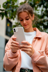 young woman smiling standing with a cell phone looking at cell phone sending message