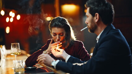 Elegant lovers smoking cigarettes at pub counter closeup. People exhaling fume