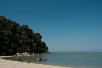 Escape to tranquility. A quiet, sunny, tropical beach scene with soft sand, gentle ocean waves, two small fishing boats, and a lush green forest hillside under a clear blue sky. Perfect vacation mood