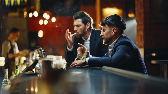 Closeup bar guests resting with alcohol cigarettes at counter talking together
