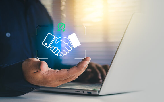 Digital business partnership concept showing a holographic handshake icon above an open laptop, building trust, agreement, and seamless collaboration for modern online services and workflows