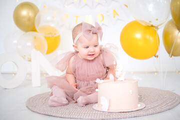 little beautiful blue-eyed girl celebrates her first birthday and tastes her first birthday cake