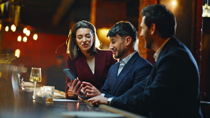 Cheerful colleagues hanging out at bar laughing together in night lounge closeup