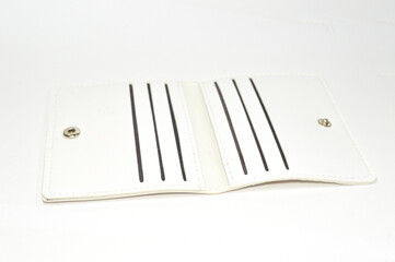 Eye-level studio shot of an open, white faux leather minimalist card holder, wallet showing six empty card slots and snap buttons, isolated on a white background. Concept for finance, payment.