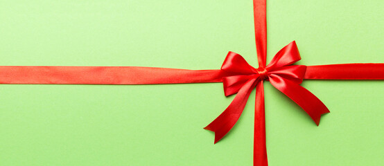 Top view of Red ribbon rolled and red bow isolated on colored background. Flat lay with copy space