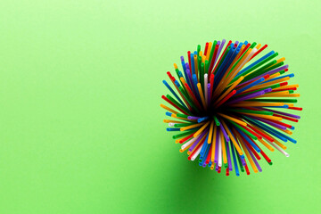 Top view of many multicolored plastic cocktail tubes in a glass. Drinking straws of bright colors Isolated on white background
