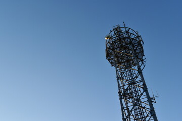 Looking up at a mobile phone tower on a sunny day.