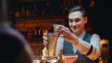 Closeup barman using shaker making cocktail in bar. Pub worker preparing drinks