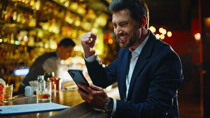 Excited businessman rejoicing online win evening bar counter closeup. Happy guy