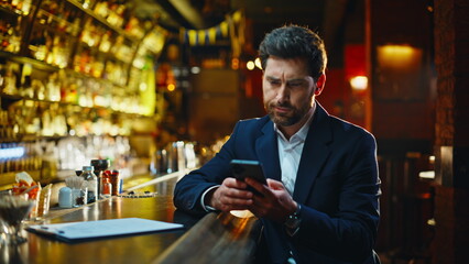 Melancholic man resting bar scrolling mobile device at night counter closeup