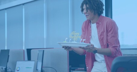 Holding red-shirt worker offering plate cake with birthday topper and candles at office, copy space