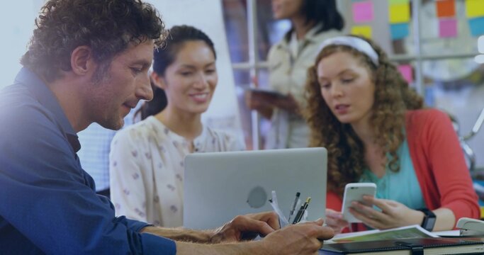 Writing male in blue shirt taking notes at coworking desk, with laptop, smartphone, copy space