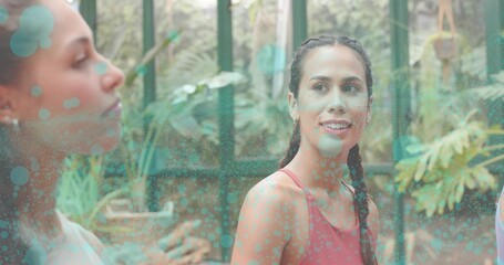Talking Pacific woman wearing red tank top and braid in greenhouse, with potted plants