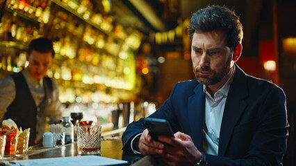Frustrated guy holding smartphone in cafe bar closeup. Heartbroken man texting