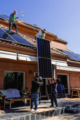 Fototapeta premium Workers installing solar panels on house roof