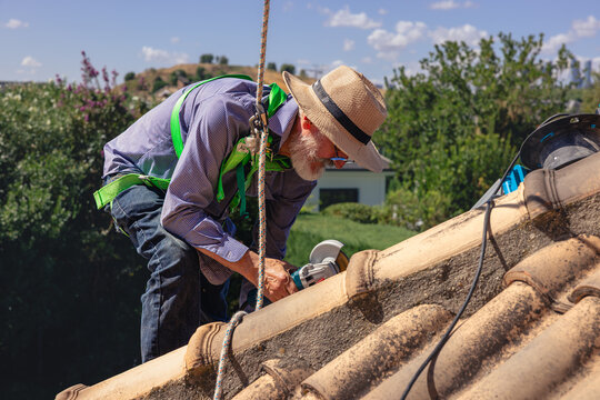 Senior man safely working on roof tile repair
