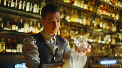 Young barista wiping glass stylish club closeup. Night bartender cleaning dishes