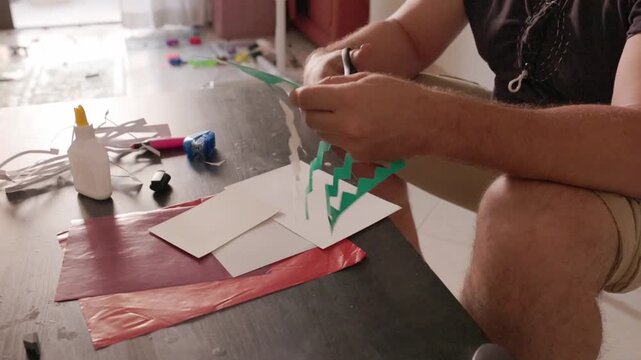 Creative man cutting paper with scissors for a diy craft project