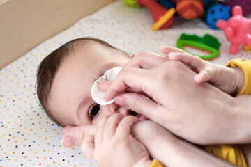 babies and newborn hygiene and healthcare. Closeup of cleaning and washing baby face with soft cottong pad
