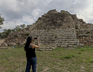 woman standing in front of ancient mayan pyramid ruins in the maya city of oxkintok in yucatan...