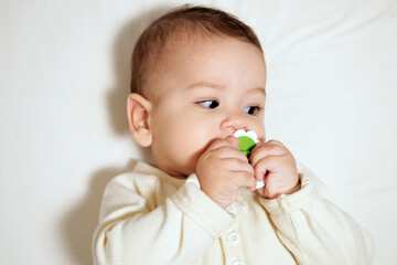 Baby sucking Pacifier looking on bed. portrait of cute newborn baby lying on bed with pacifier on mouth
