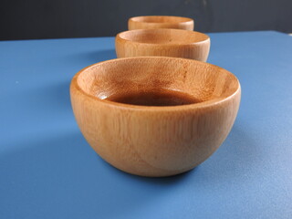 Wooden bowl on a blue background with black olive oil