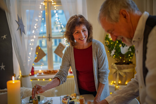 Older couple preparing table for Christmas dinner. - Powered by Adobe