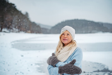 Senior woman enjoying snowfall in winter landscape.