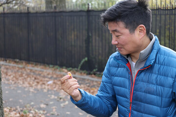 adult man examining tree plant in park horticulture expert stroll walk winter autumn blue puffy jacket puffer down coat garden gardening flora botanic botanical gaze bend pick up touch reach portrait