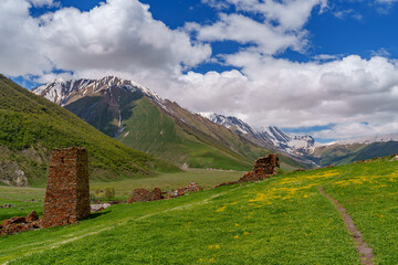 Ancient stone ruins above meadow with dramatic snowy Caucasus backdrop